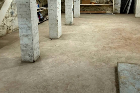 Unfinished basement with bare concrete floor and structural columns ready for professional epoxy floor coating service by Post Green Cleaning in New York.