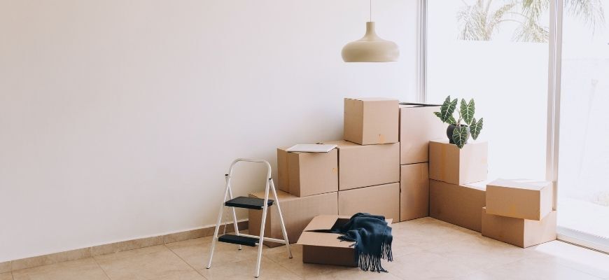 Packed moving boxes in a bright new home, representing the ultimate move in cleaning checklist before unpacking.