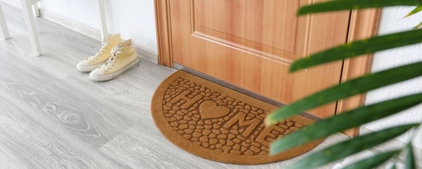 Home entryway with welcome mat, highlighting move in cleaning checklist for mudrooms and entry areas.