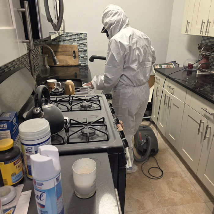 Technician in protective gear performing HEPA dust remediation in kitchen after residential ceiling collapse