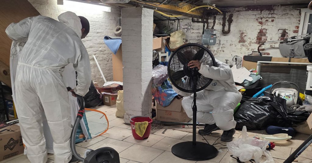 Technicians performing HEPA vacuuming and basement restoration cleaning in a residential New York home following contamination and debris buildup