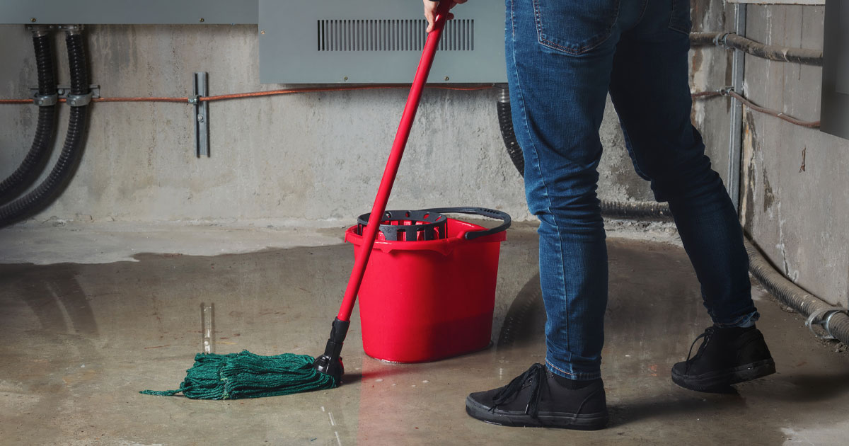 Homeowner removing water from a flooded basement floor during basement flood cleanup and water damage restoration after basement flooding