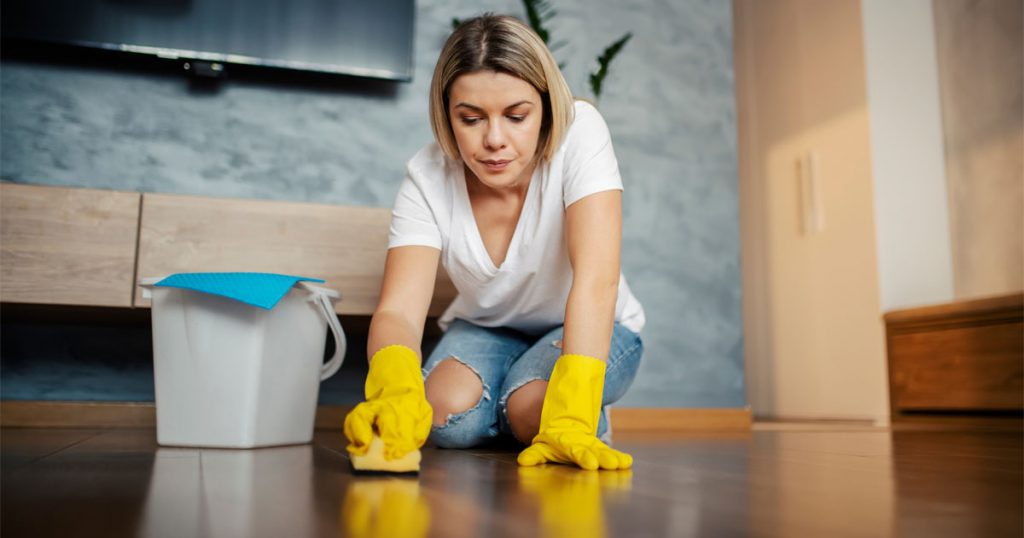 Paint buckets, dust, and renovation debris in a room with a finished living room visible beyond